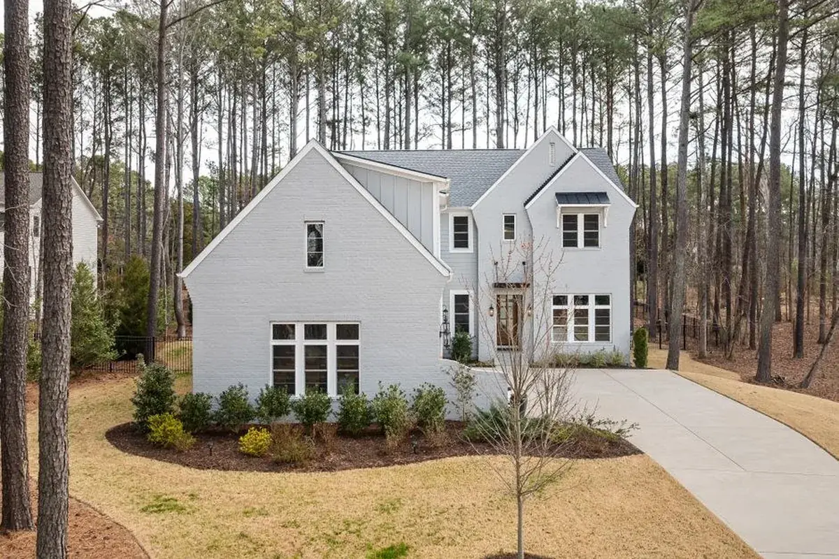 Elegant white two-story house amidst tall pine, the kind of home we buy in Klein