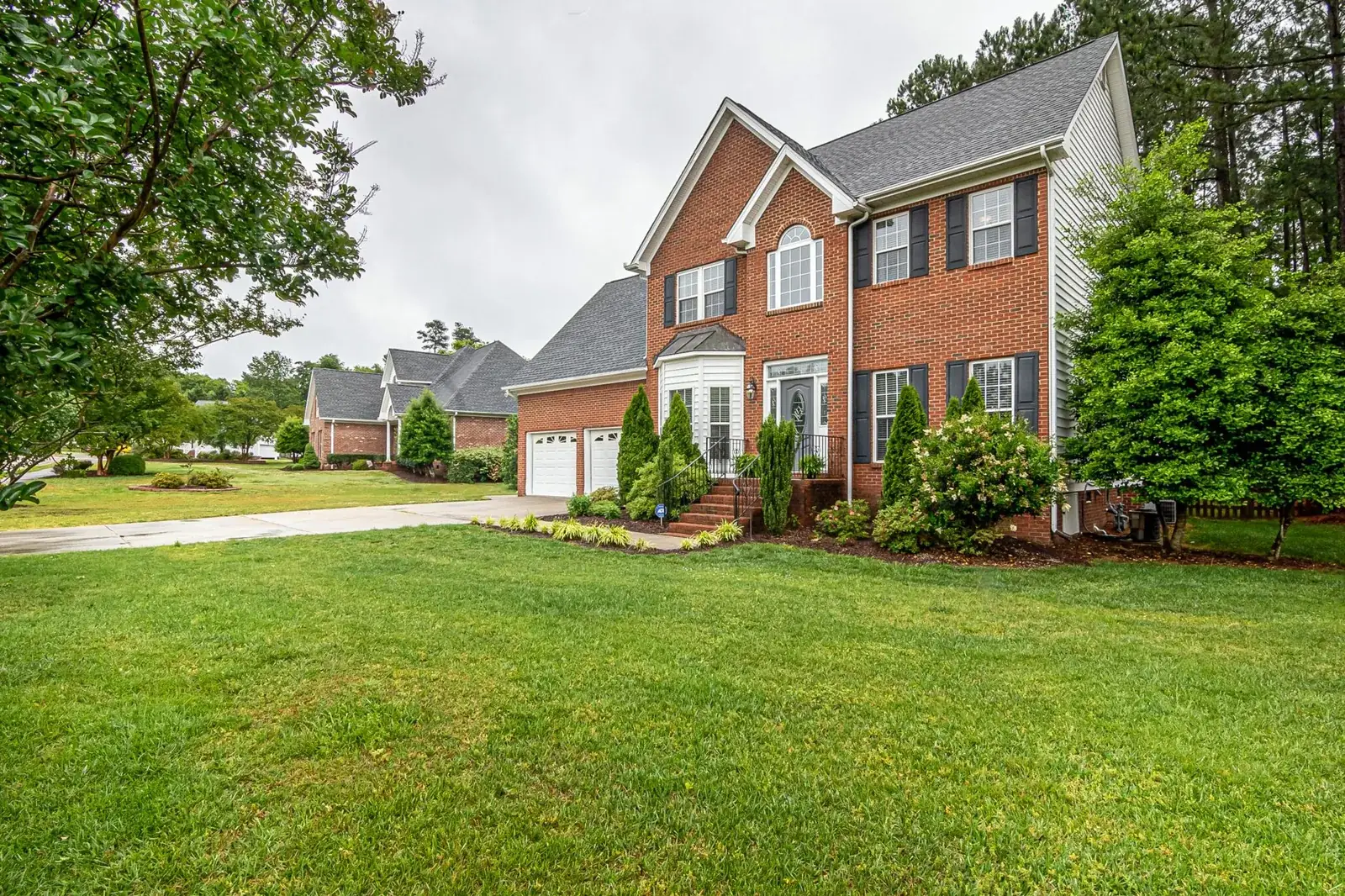 Charming two-story brick house with manicured lawn, the kind of home we buy in Magnolia