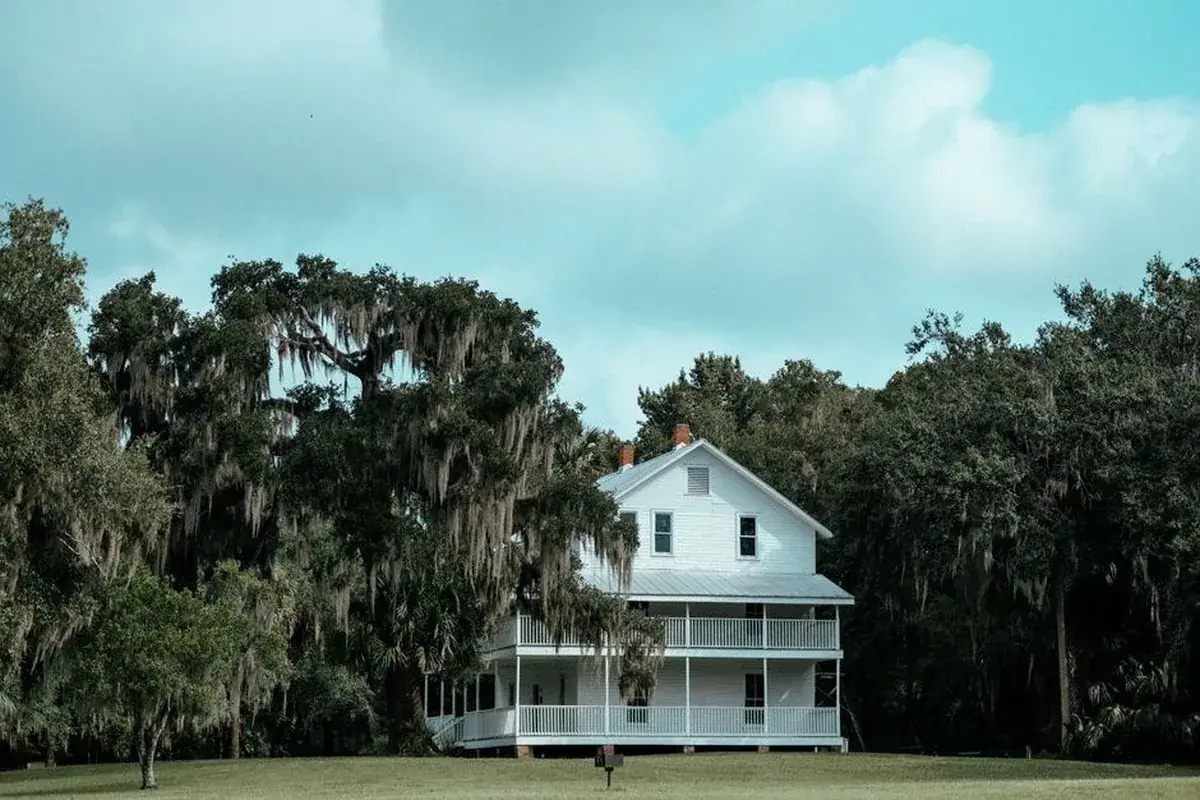 A quaint white house surrounded, the kind of home we buy in River Plantation