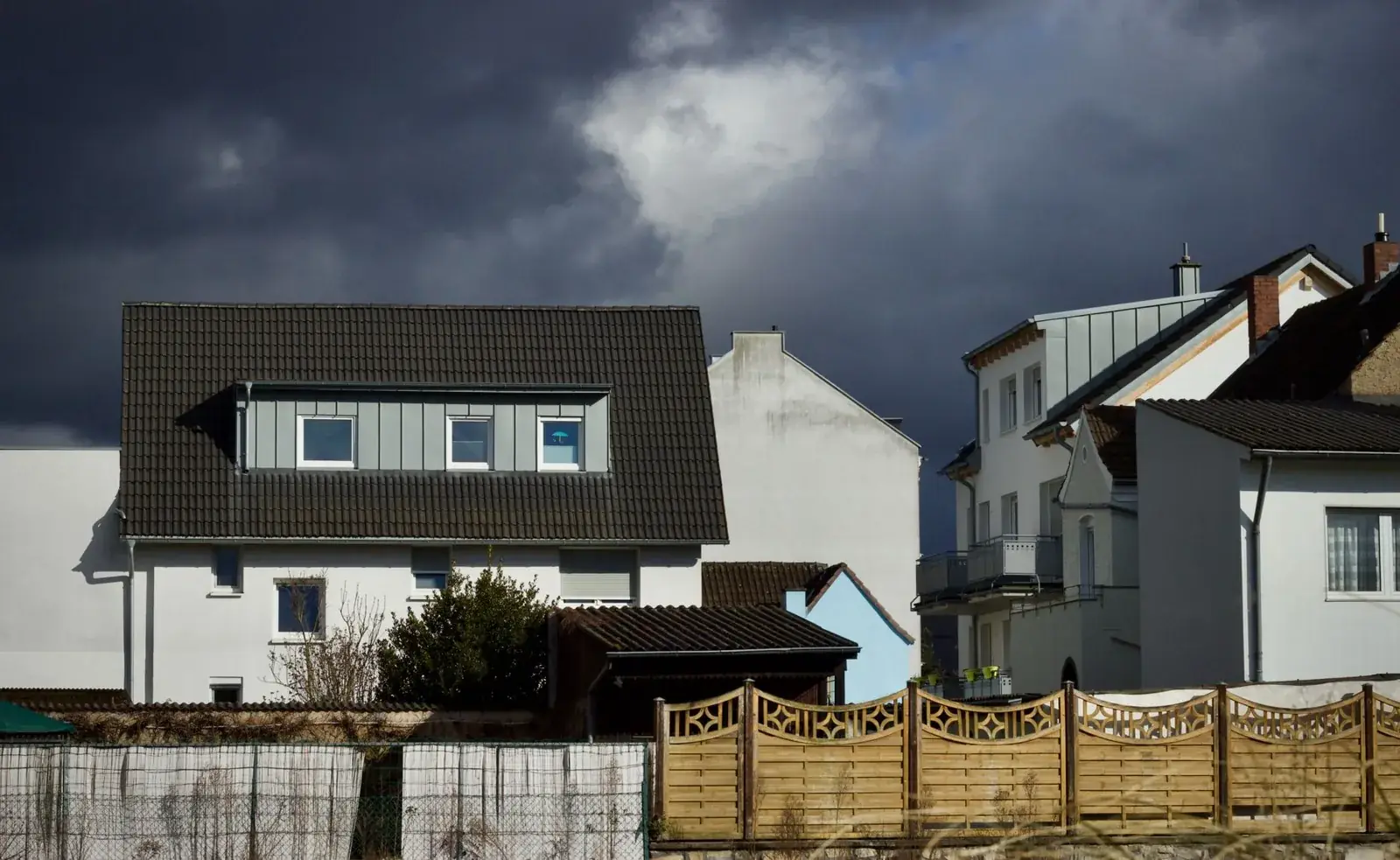 Suburban houses under a dramatic cloudy sky, the kind of home we buy in Sealy