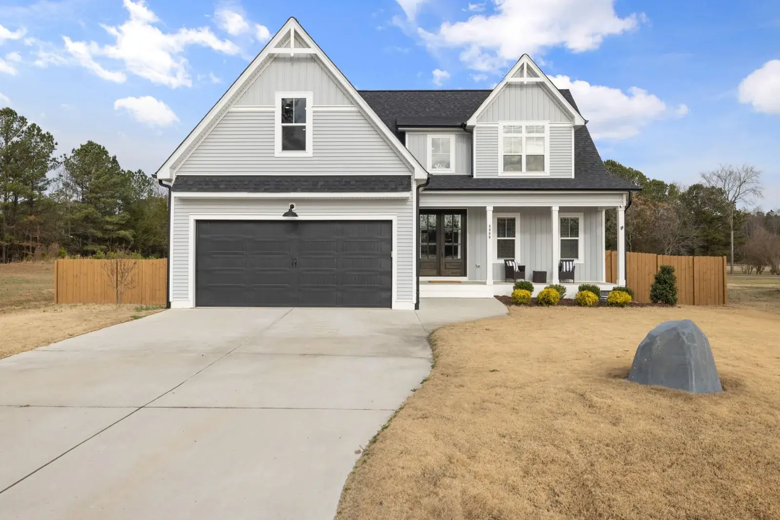 Charming two-story suburban house with black garage, the kind of home we buy in Woodloch